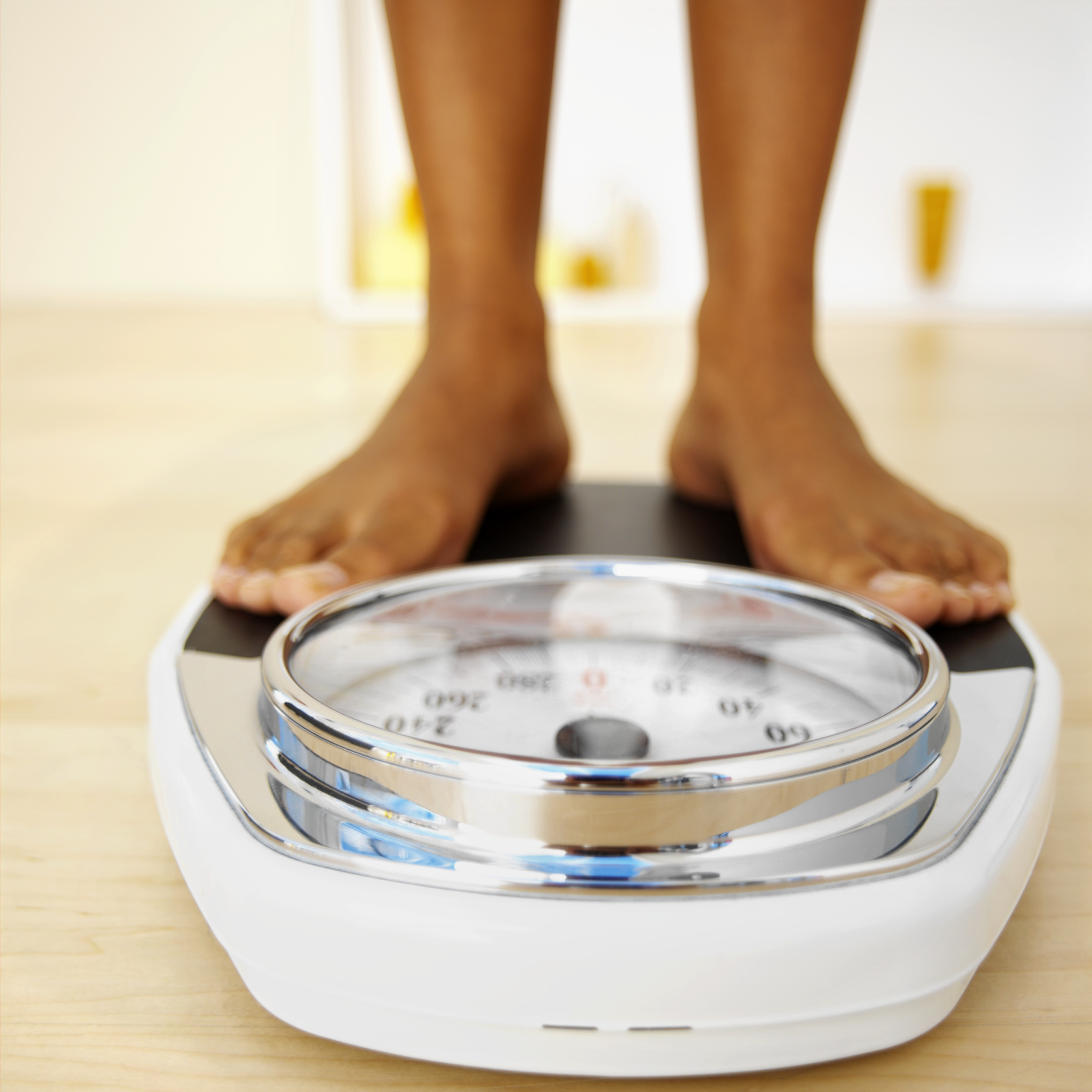 elderly woman standing barefoot on a bathroom scale and measuring